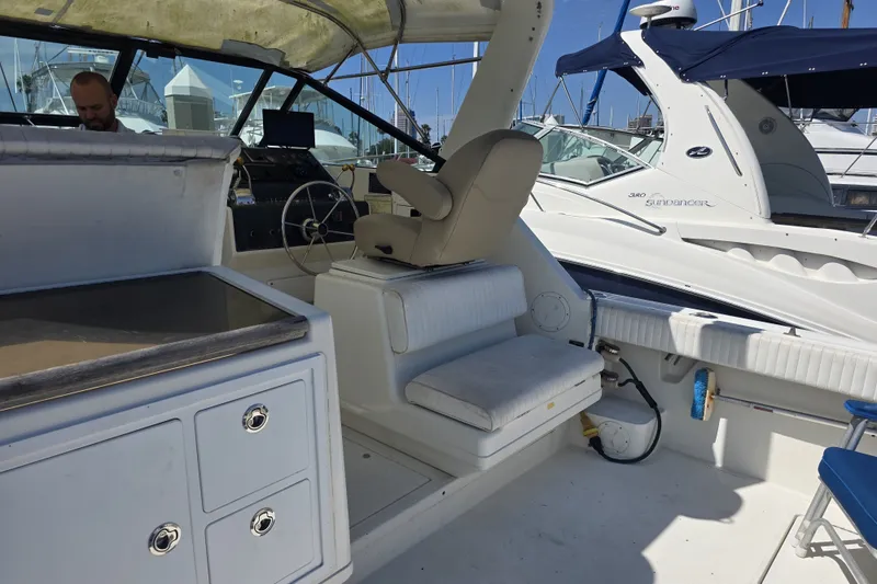 Slide: The Image of 1990 Tiara 3300 Open yacht interior with helm, seating, and docked boats in background. - 4