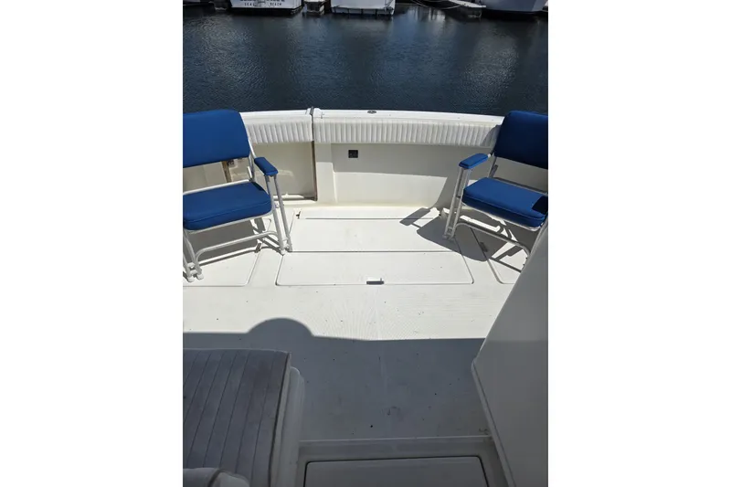 Slide: The Image of 1990 Tiara 3300 Open boat deck with blue chairs, docked at marina. - 2