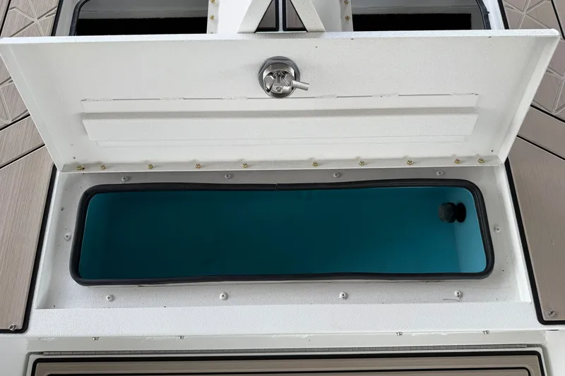 Slide: The Image of Open storage compartment on 2027 Avid 22 Recon boat, featuring a secure latch and blue interior. - 31