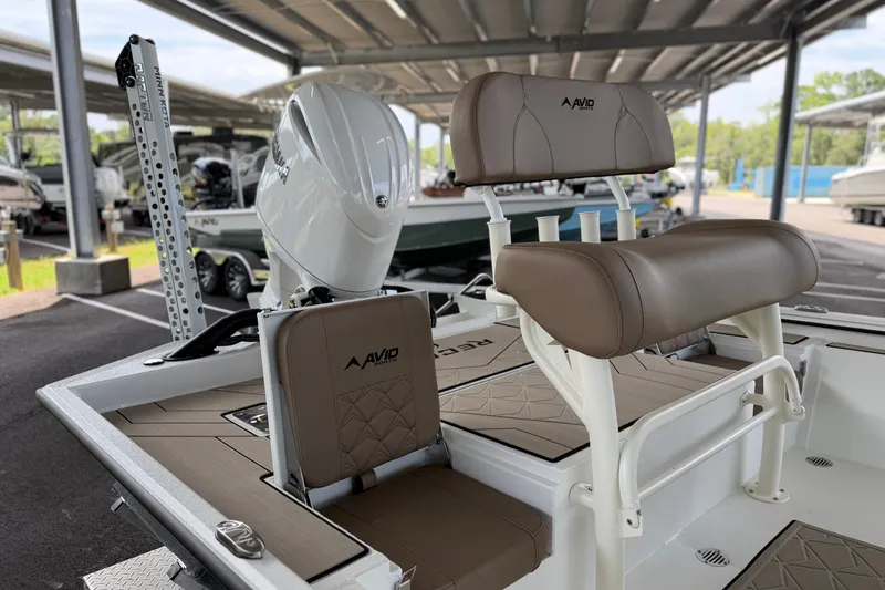 Slide: The Image of Avid 22 Recon 2027 boat interior with cushioned seating and motor, under covered storage. - 21