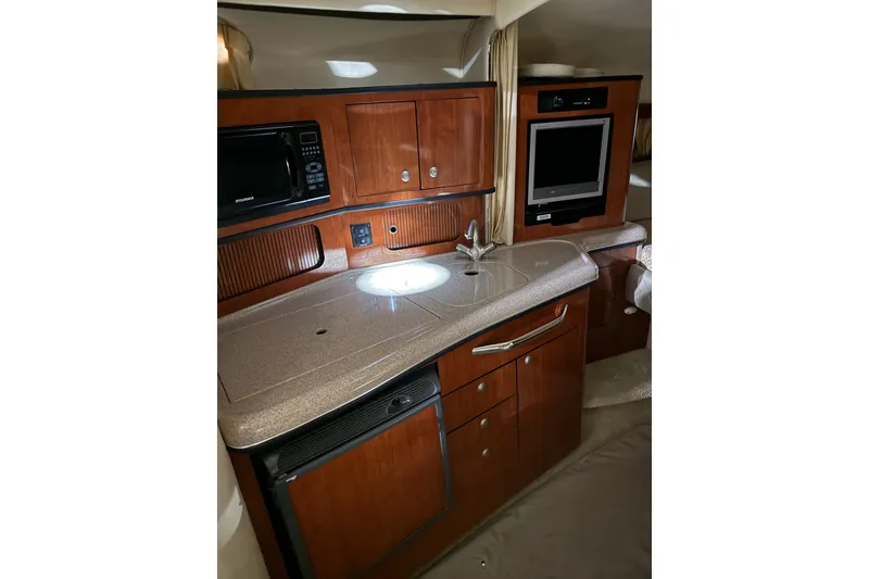 Slide: The Image of 2006 Sea Ray 300 Sundancer interior kitchen with wood cabinetry, sink, and appliances. - 10