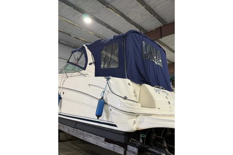 Slide: The Image of 2006 Sea Ray 300 Sundancer boat with blue canopy in indoor storage. - 3
