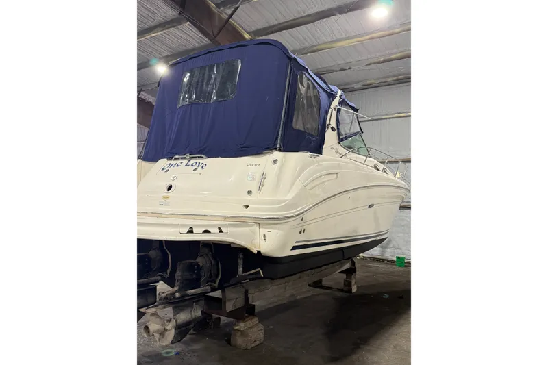 Slide: The Image of 2006 Sea Ray 300 Sundancer boat in storage, covered with a blue canopy. - 2