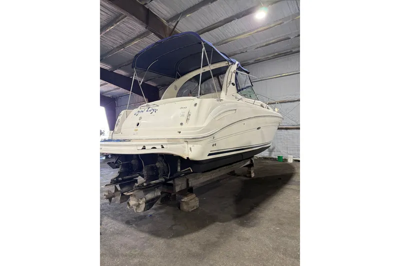 Slide: The Image of 2006 Sea Ray 300 Sundancer boat in indoor storage, rear view with blue canopy. - 4