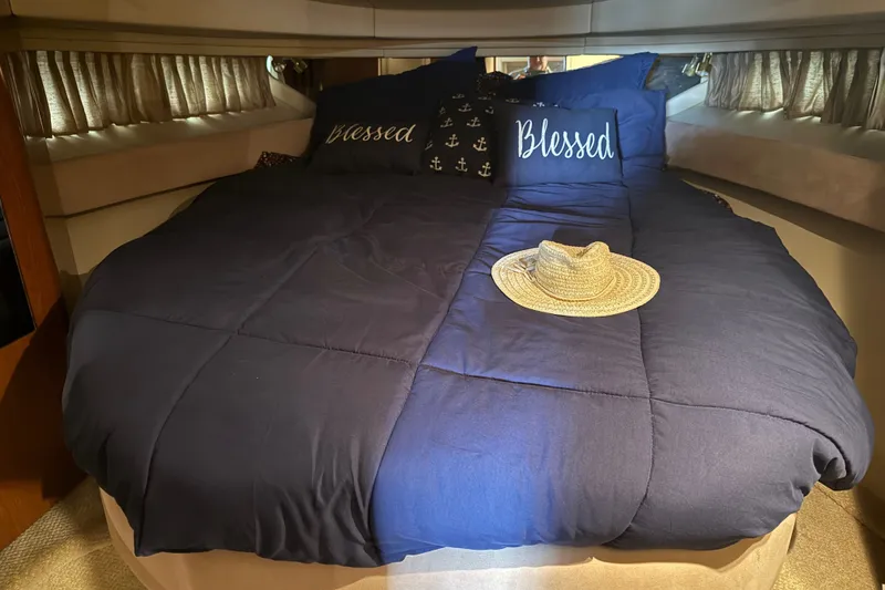 Slide: The Image of Cozy bedroom in 2002 Sea Ray 410 Sundancer yacht with navy bedding and straw hat. - 22