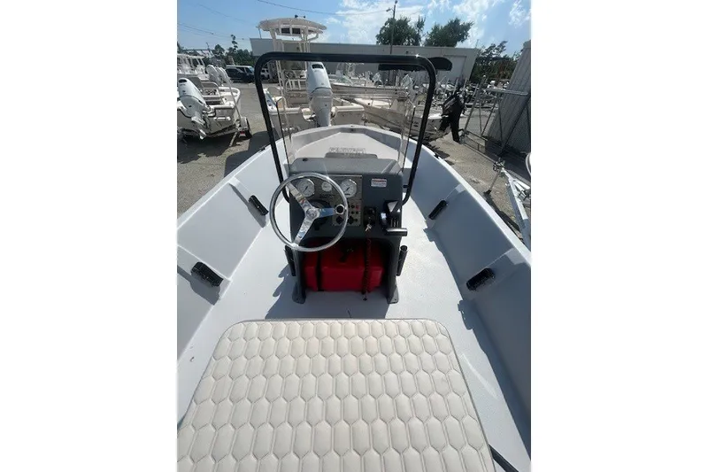 Slide: The Image of 2025 Carolina Skiff EV218 Sea Skiff interior with steering wheel and seating, docked outdoors. - 10