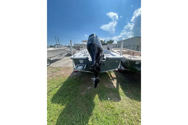 Slide: The Image of 2025 Carolina Skiff EV218 Sea Skiff with outboard motor, parked on grass under blue sky. - 12