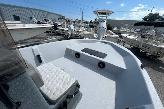 Slide: The Image of 2025 Carolina Skiff EV218 Sea Skiff boat, spacious deck, parked among other boats under clear sky. - 8