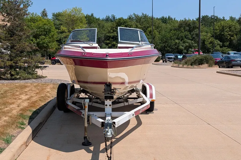 Slide: The Image of 1987 Sea Ray Sorrento 23 boat on trailer in parking lot, surrounded by trees. - 4