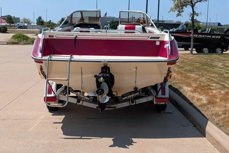 Slide: The Image of 1987 Sea Ray Sorrento 23 boat, rear view, parked on pavement, showcasing propeller and ladder. - 2