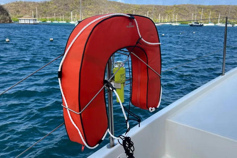 Slide: The Image of Red life preserver on Fountaine Pajot SABA 50 yacht, 2021, with ocean and boats in background. - 73
