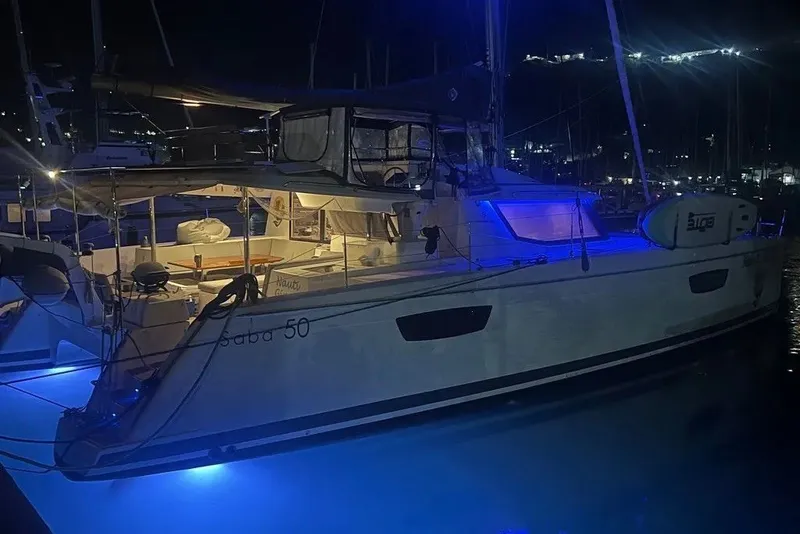 Slide: The Image of 2021 Fountaine Pajot SABA 50 catamaran illuminated at night with blue lights in a marina. - 19
