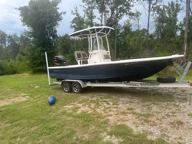 The Image of A 2019 Tidewater 2200 Carolina Bay boat on a trailer, surrounded by trees and grass. - 0