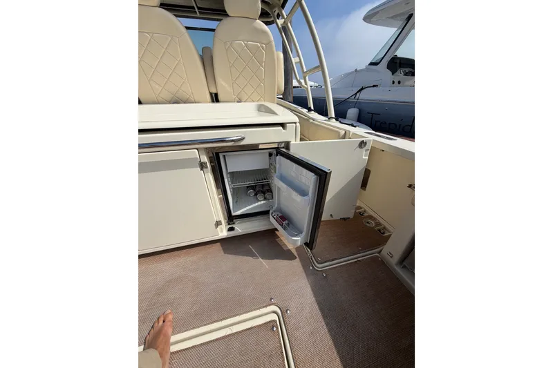 Slide: The Image of 2017 Chris-Craft Catalina 34 interior with open mini fridge and beige seating. - 16