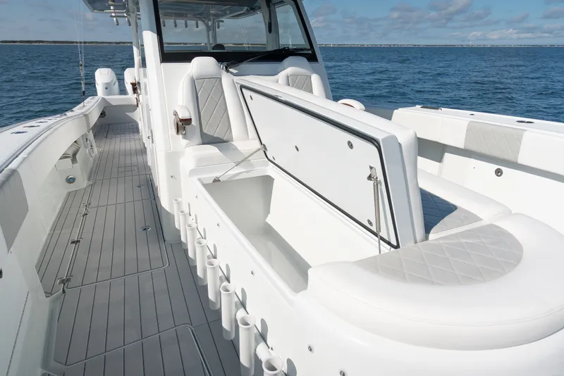 Slide: The Image of 2024 Freeman 43 boat interior with open storage, rod holders, and cushioned seating on the ocean. - 15