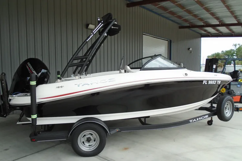 The Image of 2023 Tahoe 185 S boat on trailer, black and white design, parked in a covered area. - 0