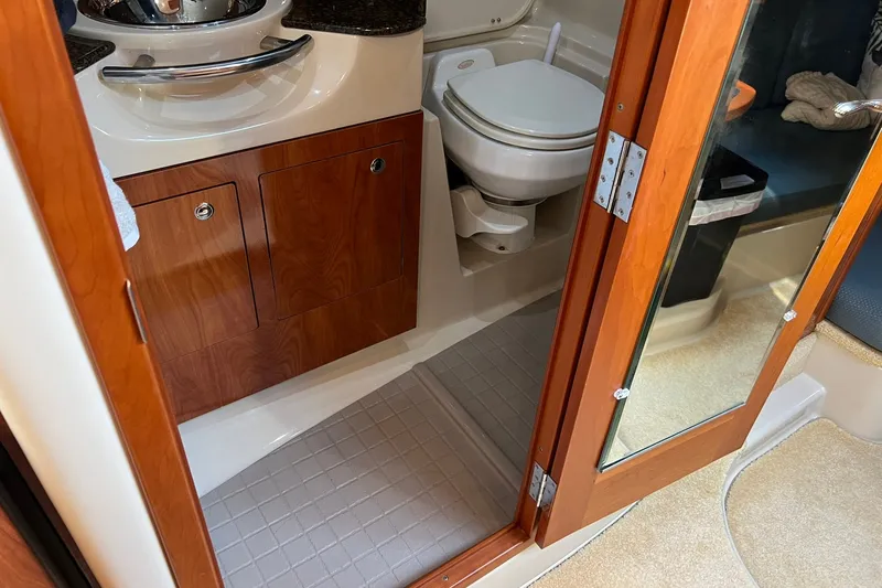 Slide: The Image of 2006 Four Winns 348 Vista boat bathroom with wooden cabinetry and compact toilet. - 9