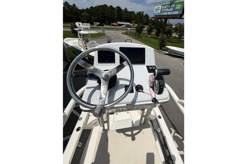Slide: The Image of 2022 Pathfinder 2600 HPS boat helm with steering wheel and controls, parked outdoors. - 14