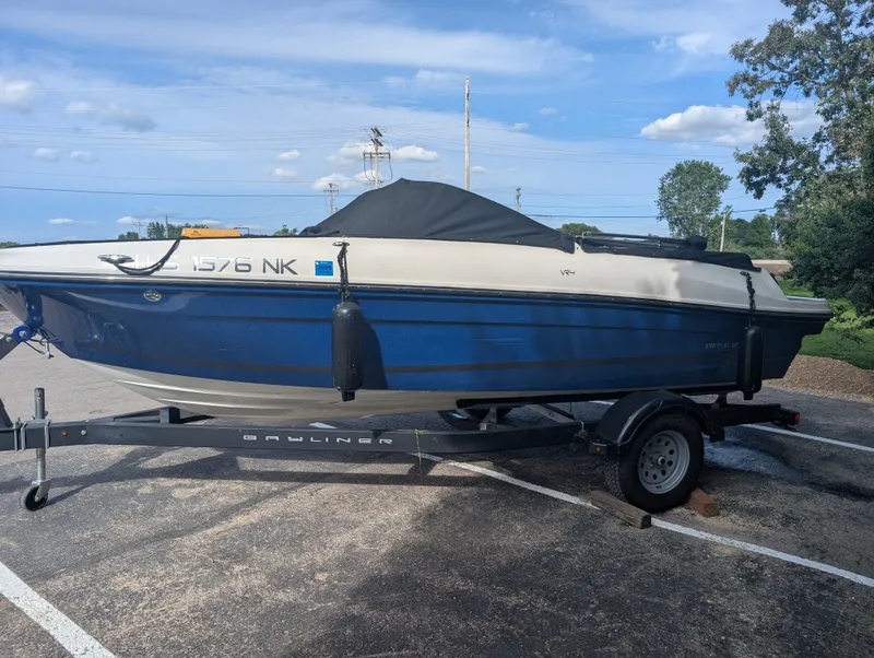 Slide: The Image of A blue and white 2023 Bayliner VR4 Bowrider on a trailer in a parking lot. - 1