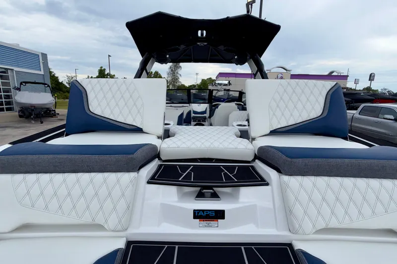 Slide: The Image of 2027 Tigé 24RZX boat interior with luxurious white and blue seating, docked outdoors. - 14
