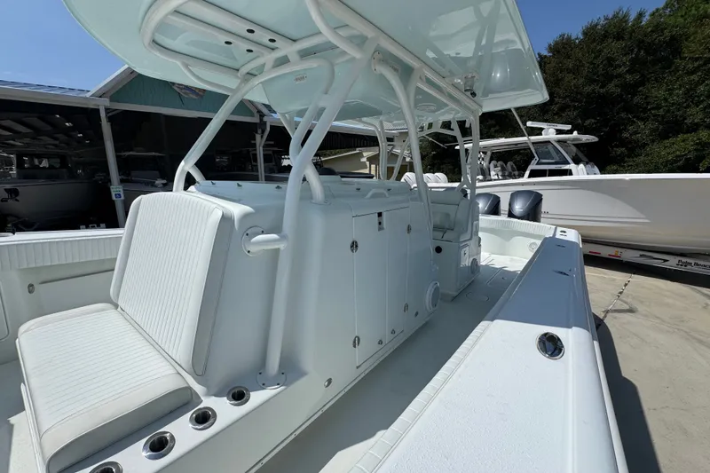 Slide: The Image of 2014 Yellowfin 39 Offshore boat with sleek white seating and console, docked outdoors. - 28