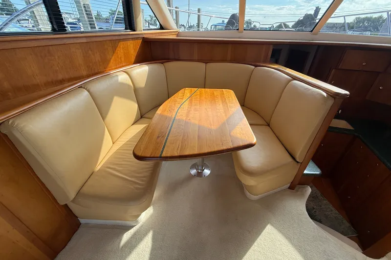 Slide: The Image of Interior of 2000 Silverton 42 Convertible yacht with cozy dining area and wooden table. - 16