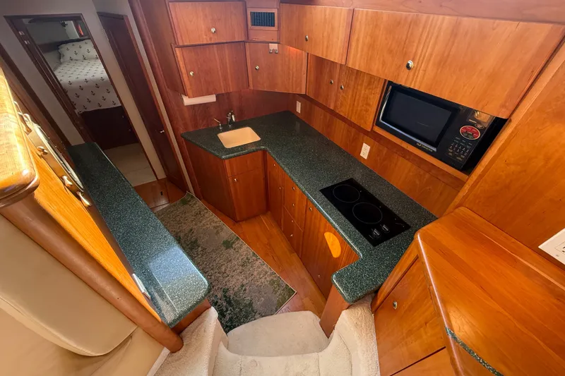 Slide: The Image of Interior of a 2000 Silverton 42 Convertible yacht kitchen with wood cabinetry and modern appliances. - 21