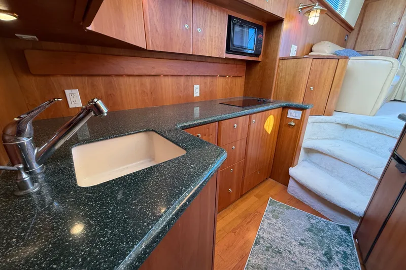Slide: The Image of Interior of 2000 Silverton 42 Convertible yacht with modern kitchen and wooden cabinetry. - 27