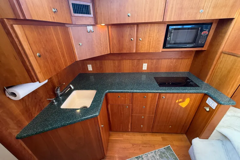 Slide: The Image of 2000 Silverton 42 Convertible yacht kitchen with wood cabinets and green countertops. - 23
