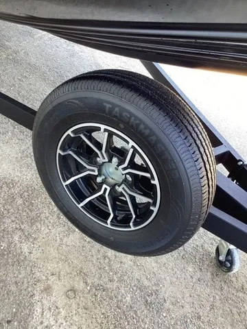 Slide: The Image of Close-up of a boat trailer wheel with a black rim and tire on concrete ground. - 23