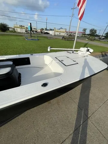 Slide: The Image of A white boat with an open deck and storage hatch, parked on concrete with a flag in the background. - 15