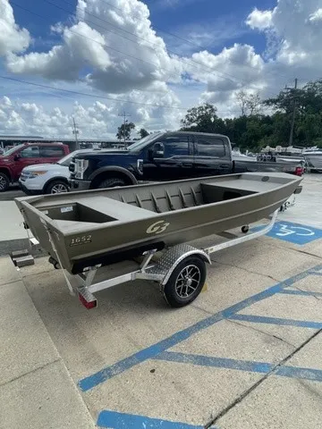 The Image of A G3 Gator Tough 1652 VBW boat on a trailer, parked in a lot under a cloudy sky. - 1