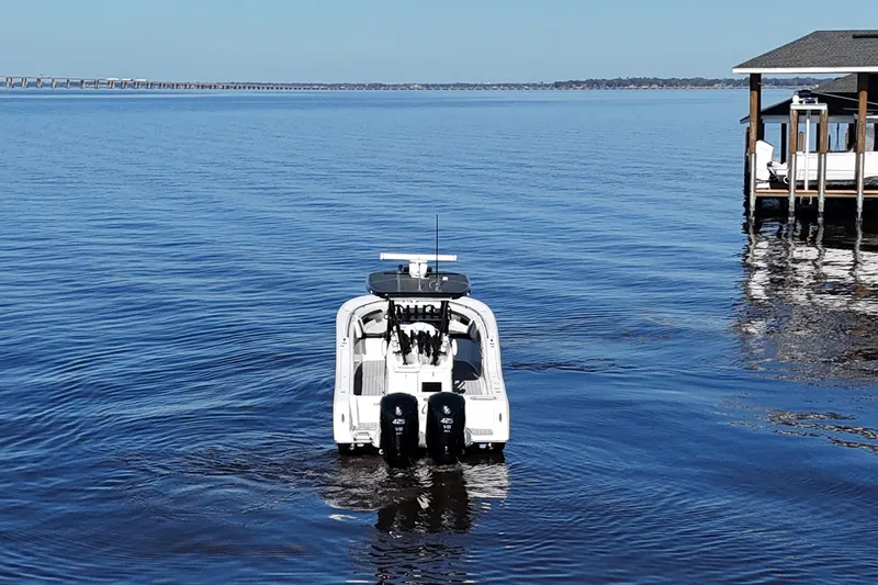 Slide: The Image of 2023 Tidewater 320 CC Adventure boat on calm water near a dock. - 5