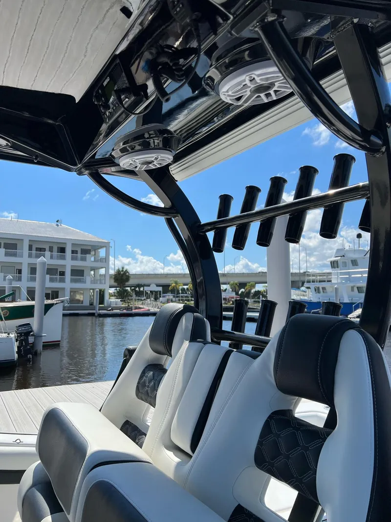 Slide: The Image of 2023 Tidewater 320 CC Adventure boat interior with rod holders and seating at marina. - 26