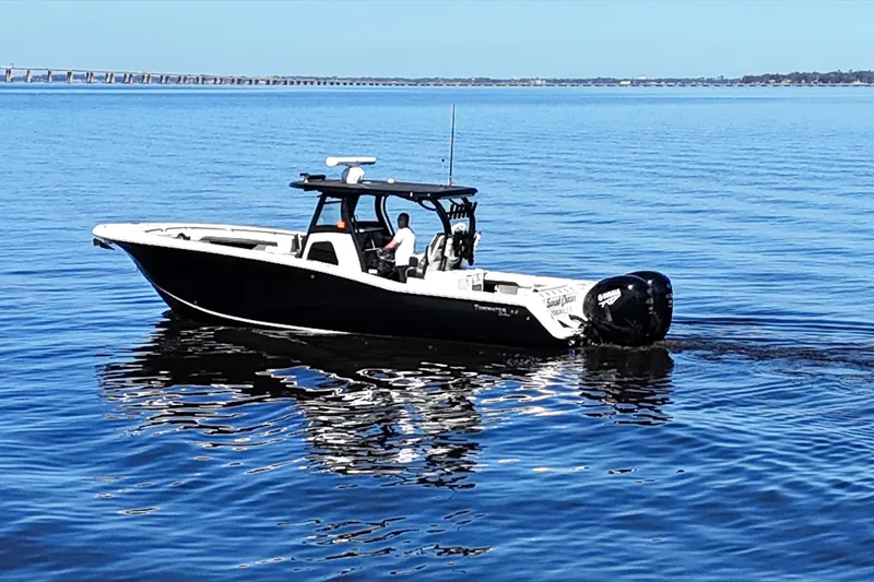 Slide: The Image of 2023 Tidewater 320 CC Adventure boat cruising on calm blue waters. - 3