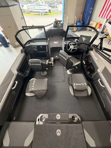 Slide: The Image of The image shows the interior of a 2027 Lund 1875 Tyee SS boat. It features four cushioned seats with Lund branding and a modern dashboard. - 2