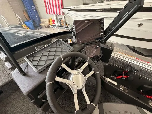Slide: The Image of The image shows the cockpit of a Lund 1875 Tyee SS boat. It features a modern steering wheel and electronic displays. - 9