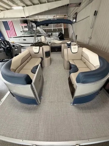 Slide: The Image of The image shows an Avalon LSZ 2385 VRB pontoon boat with beige and blue seating in a showroom. - 2
