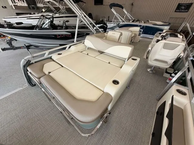 Slide: The Image of A luxurious pontoon boat with beige and gray upholstery, surrounded by other boats in a showroom. - 12