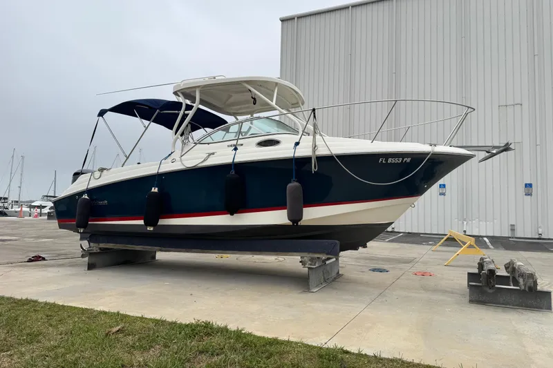 Slide: The Image of 2014 Wellcraft 252 Coastal boat on dry dock, blue hull, white cabin, marina background. - 6