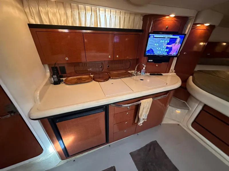 Slide: The Image of 2003 Sea Ray 340 Sundancer galley with TV, sink, and wooden cabinetry. - 43