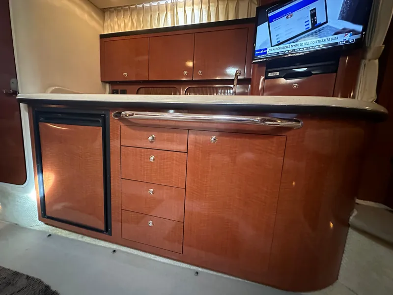 Slide: The Image of 2003 Sea Ray 340 Sundancer yacht interior with wooden cabinetry and TV. - 49