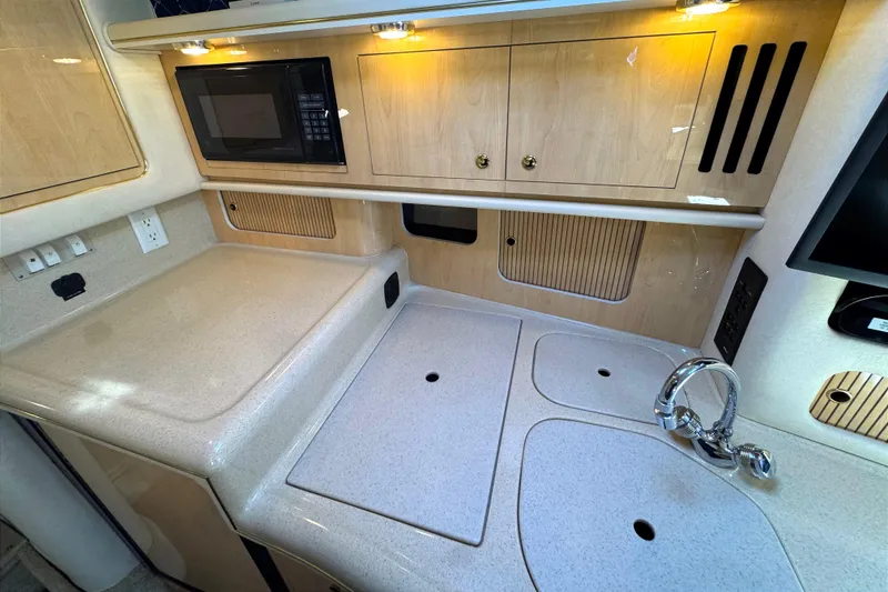 Slide: The Image of 2001 Sea Ray 340 Sundancer kitchen area with microwave, sink, and storage cabinets. - 28