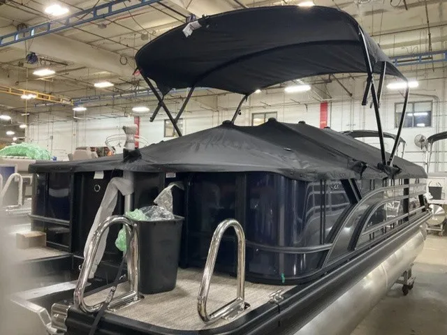 Slide: The Image of A 2027 Bennington S Fishing 22 SFC Tritoon in a warehouse with a black canopy. - 20