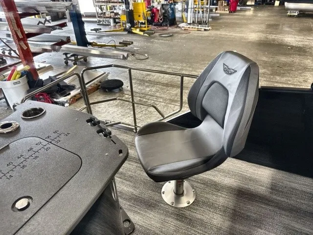 Slide: The Image of A modern boat seat with black upholstery and armrests in a workshop setting. - 17