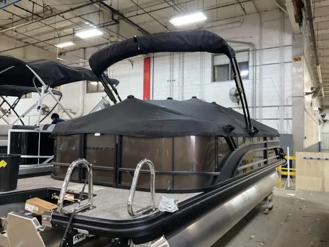 Slide: The Image of A 2027 Bennington S Quad Bench 22 SSR Tritoon is in a warehouse, covered with a tarp. - 19