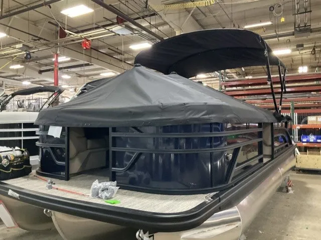 Slide: The Image of A 2027 Bennington S Fishing 22 SFC Tritoon in a warehouse, featuring a black canopy. - 19