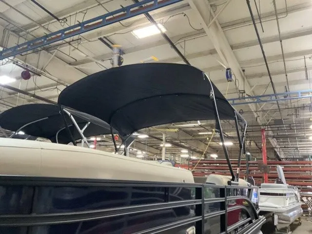 Slide: The Image of A 2027 Bennington S Fishing 22 SFC Tritoon in a warehouse with a black sunshade. - 18