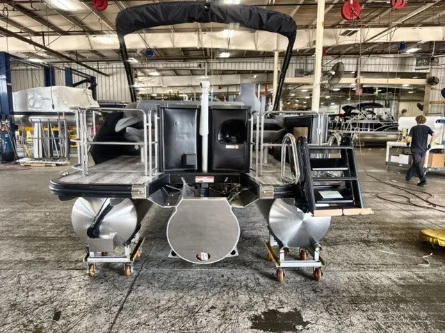Slide: The Image of The image shows a 2027 Bennington M Fishing 22 MFC Tritoon in a workshop. It features three hulls and a black cover. - 7