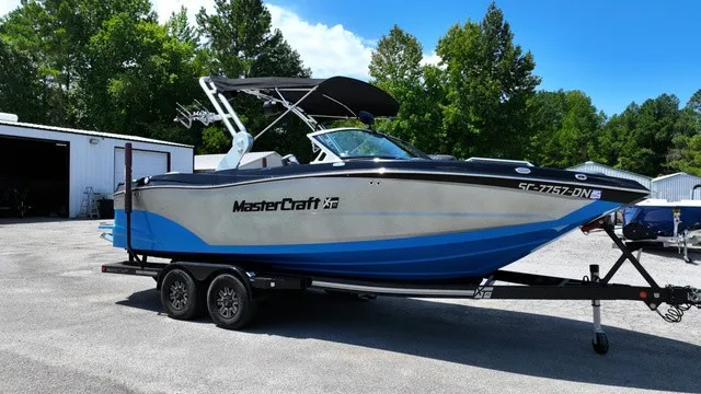 Slide: The Image of A 2019 MasterCraft XT22 on a trailer, surrounded by trees and buildings. - 10
